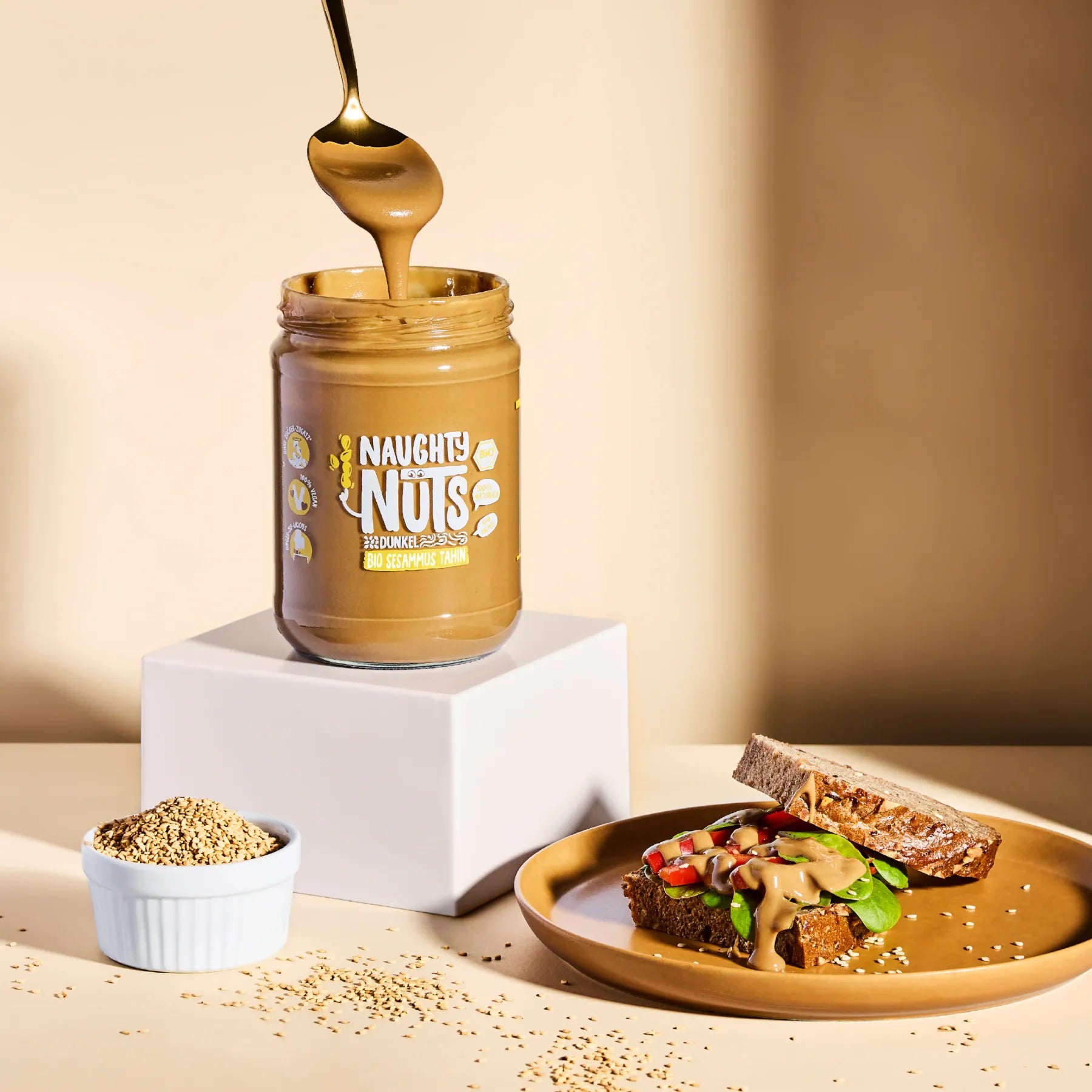 Bio Sesammus Tahin dunkel im Glas mit Löffel und belegtem Vollkornbrot
