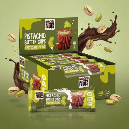 Verkaufsdisplay mit Naughty Nuts Bio Pistazienbutter Cups Salted Pistachio und fliegenden Pistazien