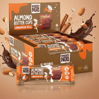 Verkaufsdisplay mit Naughty Nuts Bio Almondbutter Cups Cinnamon Roll und einzelner Riegel im Vordergrund