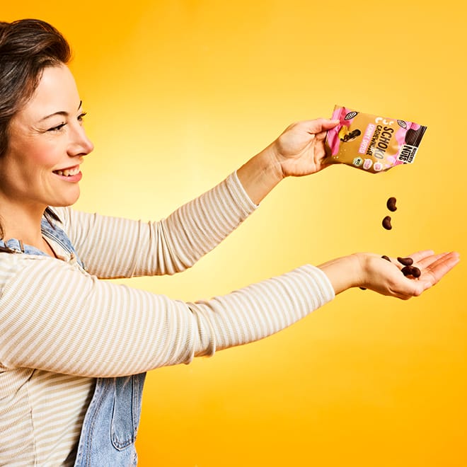 Schoko Cashews werden aus der Packung in eine Hand geschüttet