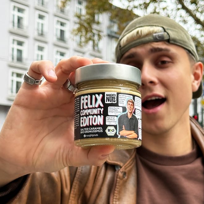 Junger Mann hält ein Glas Limited Felix Community Edition Erdnussmus Salted Caramel